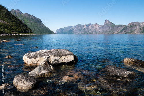 Rocky beach from Senja, Norway with mountain peaks in the background on a sunny day in summer photo