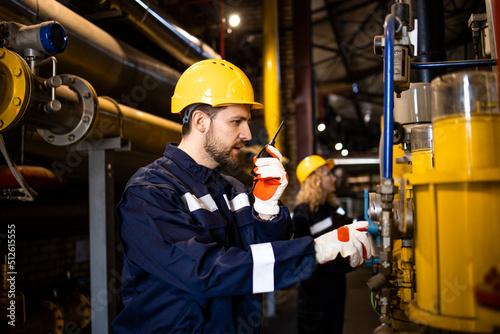 Factory workers working together in power plant controlling gas pipeline installations.