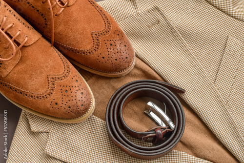 Men brown suede brogue shoes combined with light beige blazer and leather belt. Selective focus