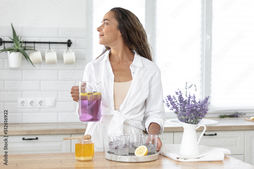 A young girl makes lemonade from lemons and lavender. Woman making a summer drink. A young girl makes lemonade from lemons and lavender. Woman making a summer drink.