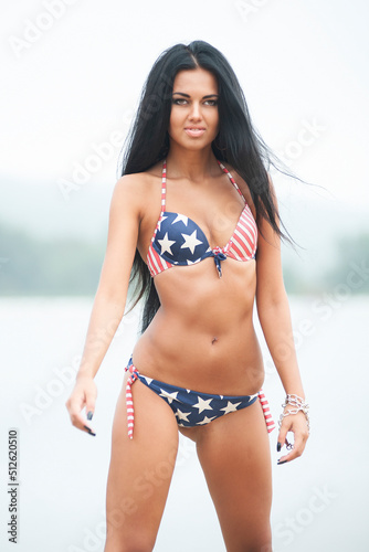 American USA flag bikini girl beach party vacation on summer holidays. Young woman with slim body wearing fashion swimsuit for 4th of July independence day celebration.