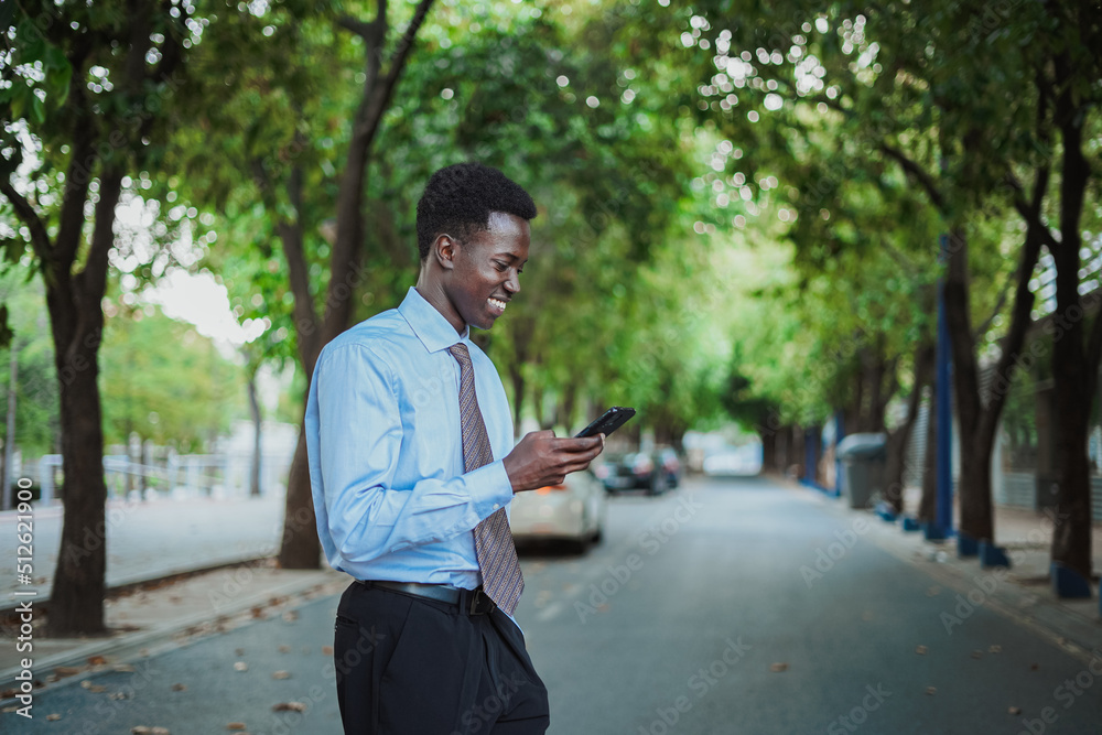 Happy african businessman sending a text message using his smart phone. Happy african businessman sending a text message using his smart phone.