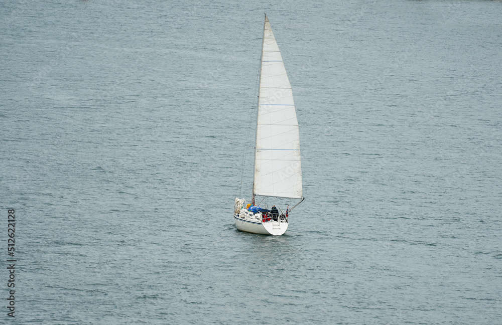 Small Sailboat or leisure Yacht sailing on calm seas. Full sails out. 