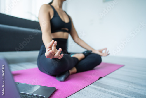 Asian woman in sports bra exercising in her own home, work at home concept