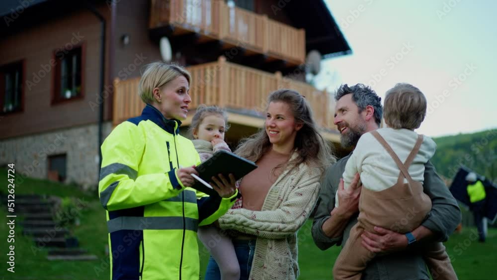 Woman engineer talking to young family about solar panel installation in front of their house.