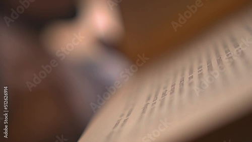 Young man flips the pages of a vintage book in a library. Guy touches aged book pages to feel the texture of a paper. Ancient volume of a rare edition of a book in an archive. Dissertation writing.