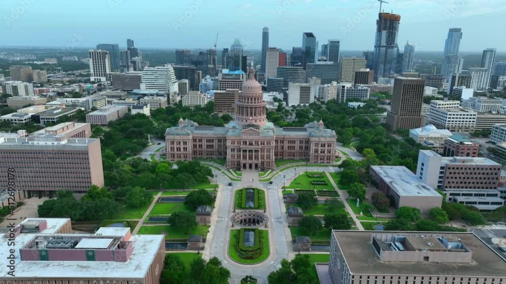 Dramatic aerial flight over dome and statue reveals downtown urban Austin Texas cityscape. TX Capitol home of state government.
