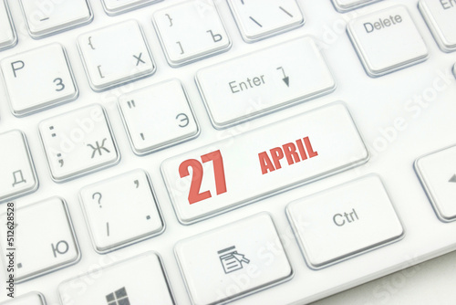 April 27th. Day 27 of month, Calendar date. Cropped view of Modern White Computer Keyboard with calendar date. Concept workspace, freelance, deadline.  Spring month, day of the year concept.