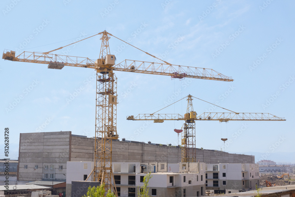 Industrial background of construction cranes at the construction site build residential buildings of block flat or apartment from modern concrete panels
