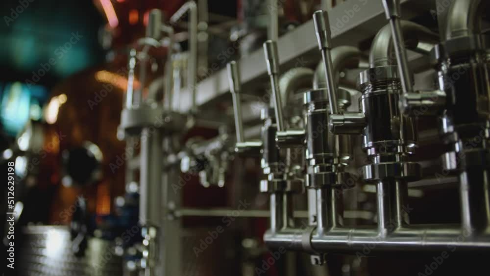 Camera moving across metallic tubes inside alcohol drinks factory. Wine , vodka cognac distilling tanks . Metal taps or kegs for pouring alcohol . slow motion close-up . Row of chrome pipes in factory Camera moving across metallic tubes inside alcohol drinks factory. Wine , vodka cognac distilling tanks . Metal taps or kegs for pouring alcohol . slow motion close-up . Row of chrome pipes in factory