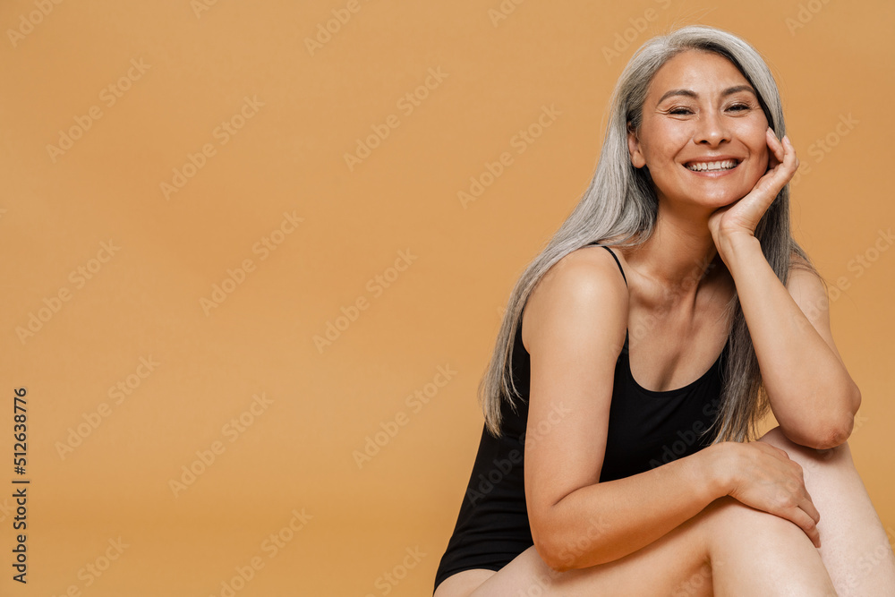 Mature asian woman wearing bodysuit smiling and posing at camera
