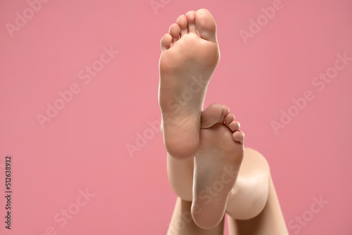 Beautiful woman's bare feet against a pink background