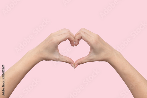Women s hands show a heart sign with fingers. On a pink background.