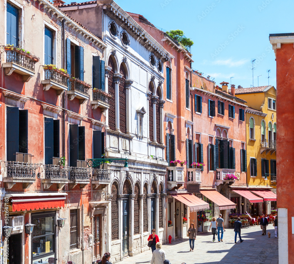 Winding street with colorful facades of buildings on a sunny morning, Venice, Italy