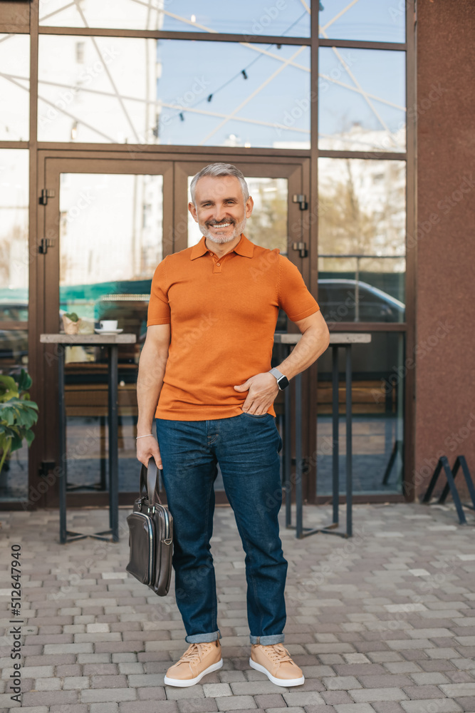 Man with suitcase standing outdoors smiling at camera Man with suitcase standing outdoors smiling at camera