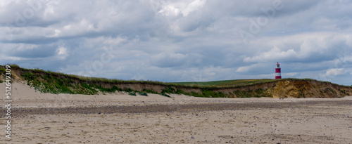 panorama landscape of Happisburgh beach and lighthouse with tall sand dunes and cliffs