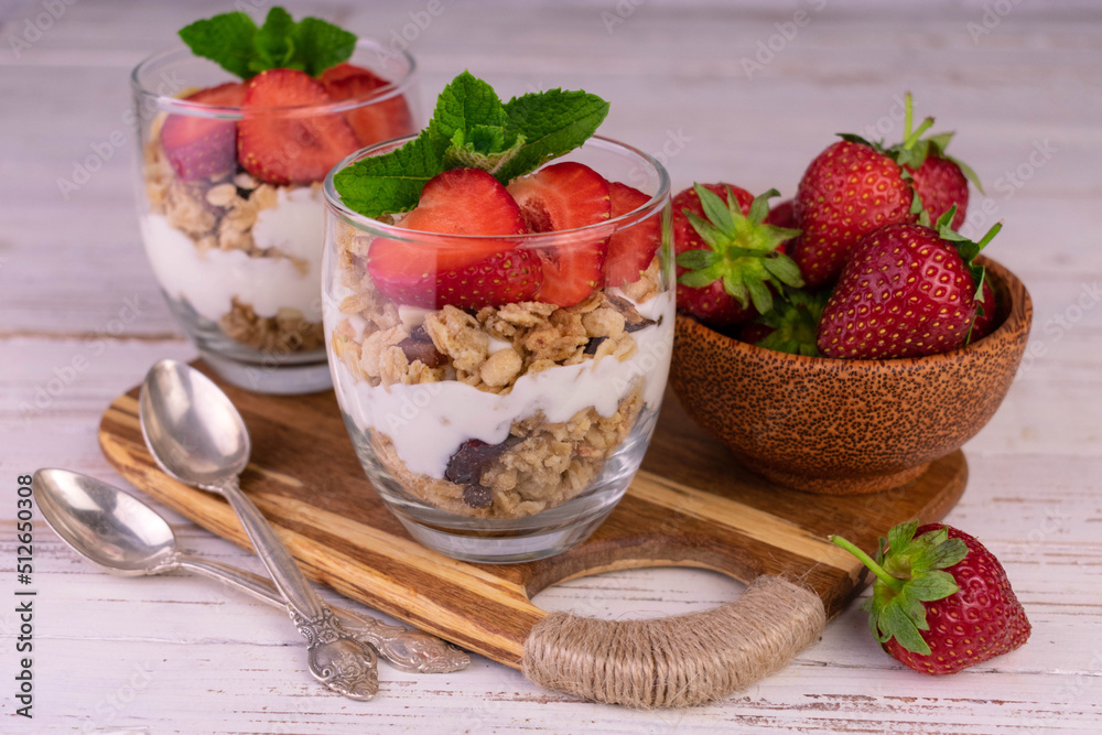 Two strawberry desserts with yogurt and granola.