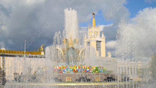 Fountain with gold details on background of historical building. Action. Beautiful large fountain with stone flower and gems works on summer day