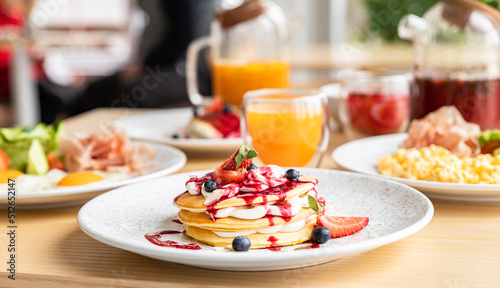 Healthy breakfast served with tea, oatmeal porridge, cottage cheese fritters, pancakes, scrambled and fried eggs in a cafe with kinfolk style interior. Breakfast concept.