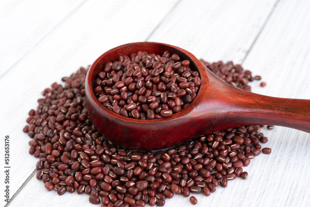 Azuki beans in wooden scoop on white table background Azuki beans in wooden scoop on white table background