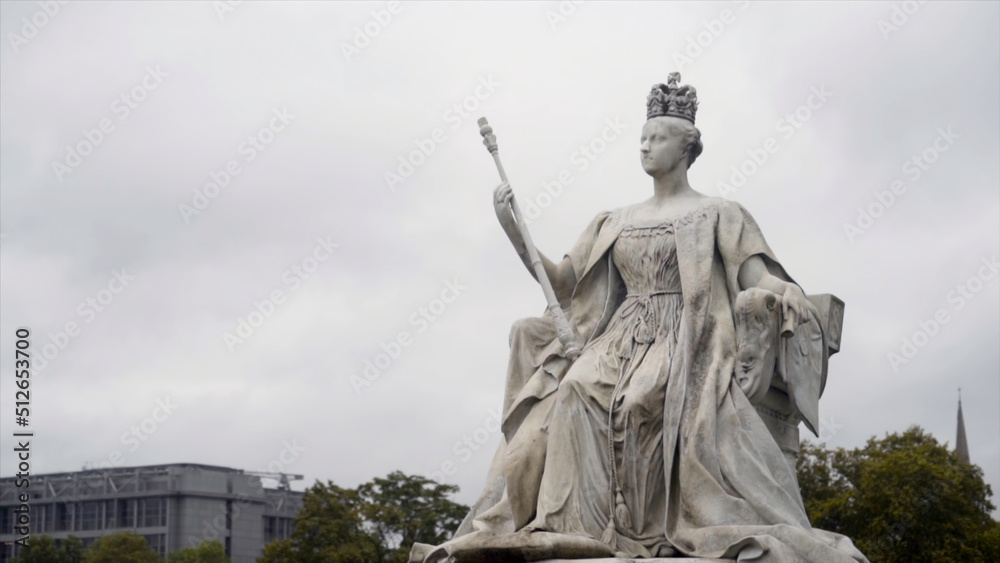 Queen monument on cloudy sky background. Action. Old beautiful sculpture of Queen of white stone in cloudy weather. Monument to great Queen