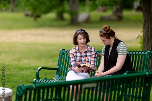 Two women doing a Bible study on a park bench