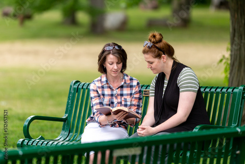 Two women studying the Bible on a park bench