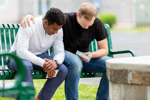 Two men praying on a bench photo