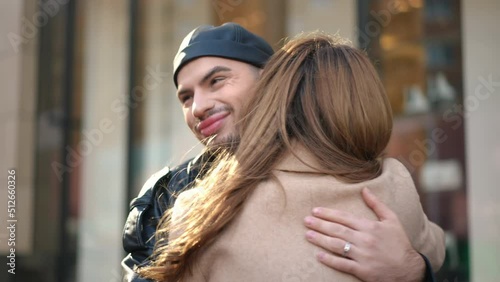 Hypocritical gay man hugging friend rolling eyes smiling. Portrait of insincere young Caucasian LGBTQ person meeting woman outdoors on city street embracing. Hypocrisy and dissimulation concept photo