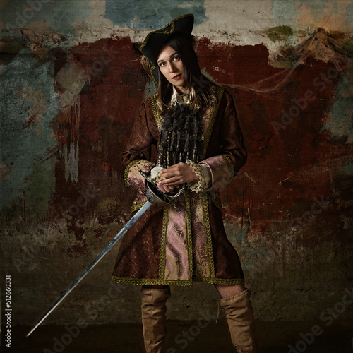 retro portrait of a musketeer girl in a hat with a sword. photo