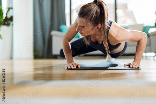 Young woman exercising push-ups at home
