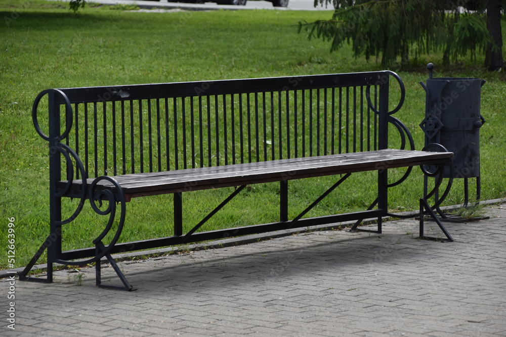 A large wooden bench in the city park in summer A large wooden bench in the city park in summer
