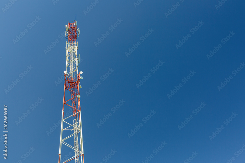 Telecommunication tower or mast with microwave, radio panel antennas, outdoor remote radio units, power cables, coaxial cables, optic fibers are installed on the top mast and blue sky as background Telecommunication tower or mast with microwave, radio panel antennas, outdoor remote radio units, power cables, coaxial cables, optic fibers are installed on the top mast and blue sky as background