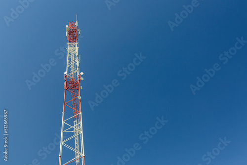 Telecommunication tower or mast with microwave, radio panel antennas, outdoor remote radio units, power cables, coaxial cables, optic fibers are installed on the top mast and blue sky as background