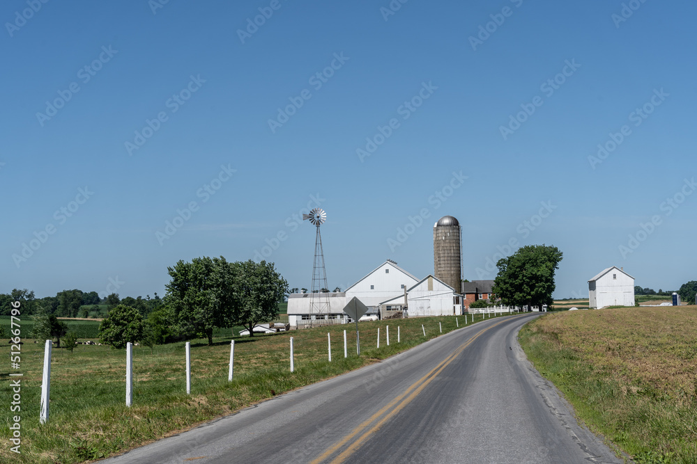 Amish Farm with windmill against blue sky background.
