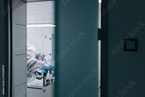 The process of preparing and cleaning teeth. A female professional dentist and an assistant are working. Photo through the door