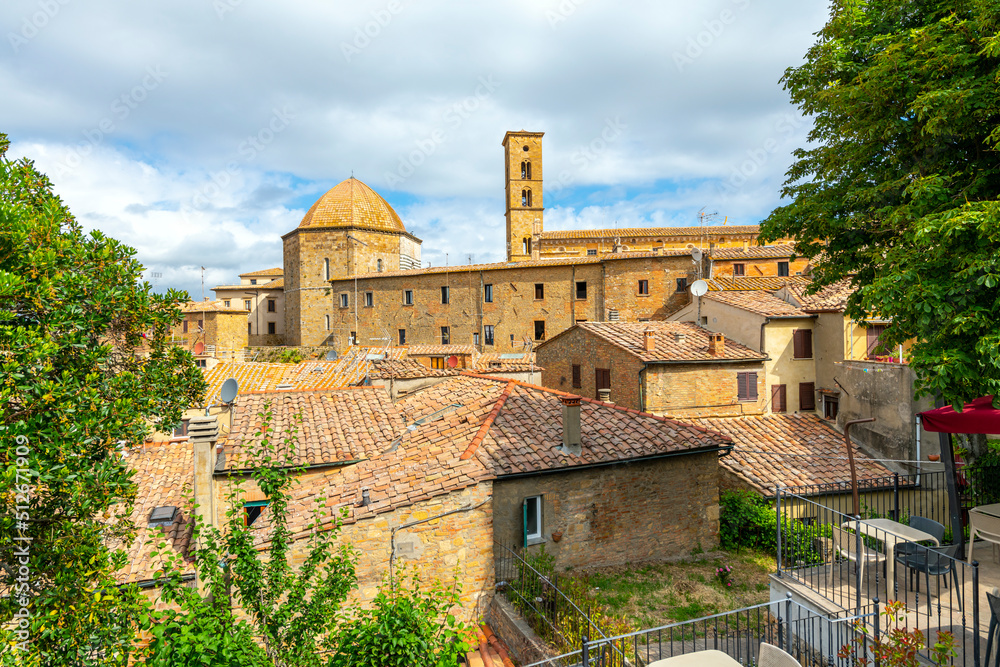 View of the Duomo cathedral dome and the Palazzo dei Priori tower in the medieval hilltop town of Volterra with the valley and hills of Tuscany in the distance.