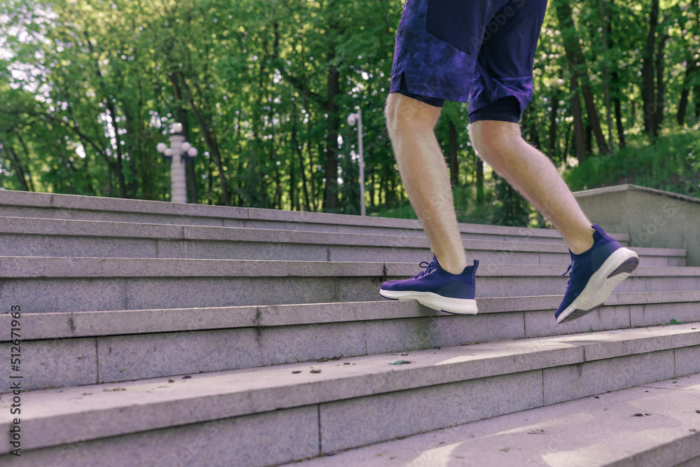 Man athlete legs running up stairs training intense cardio work out exercise, male runner feet jogging in city park