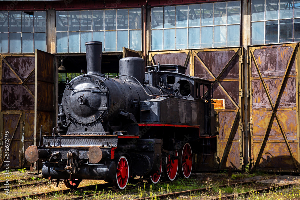 Naklejka premium A steam locomotive standing outside of historic locomotive shed. The shot was taken in natural lighting conditions