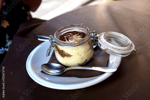 Italian tiramisu dessert in a glass jar, served in cafe