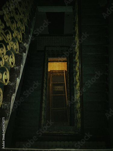 Old Square Spiral staircase perspective, view from above. Green stairwell taken from the top view. Horror mood