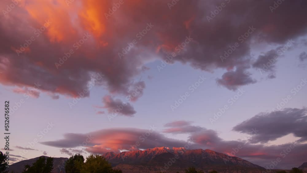 Colorful lenticular clouds rolling in the sky during colorful sunset looking towards Timpanogos Mountain in Utah. Colorful lenticular clouds rolling in the sky during colorful sunset looking towards Timpanogos Mountain in Utah.
