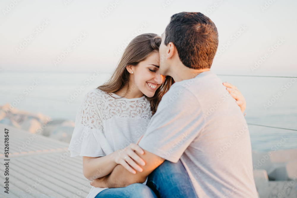 Hispanic man and a smiling brunette girl are sitting on a breakwater in Spain Hispanic man and a smiling brunette girl are sitting on a breakwater in Spain