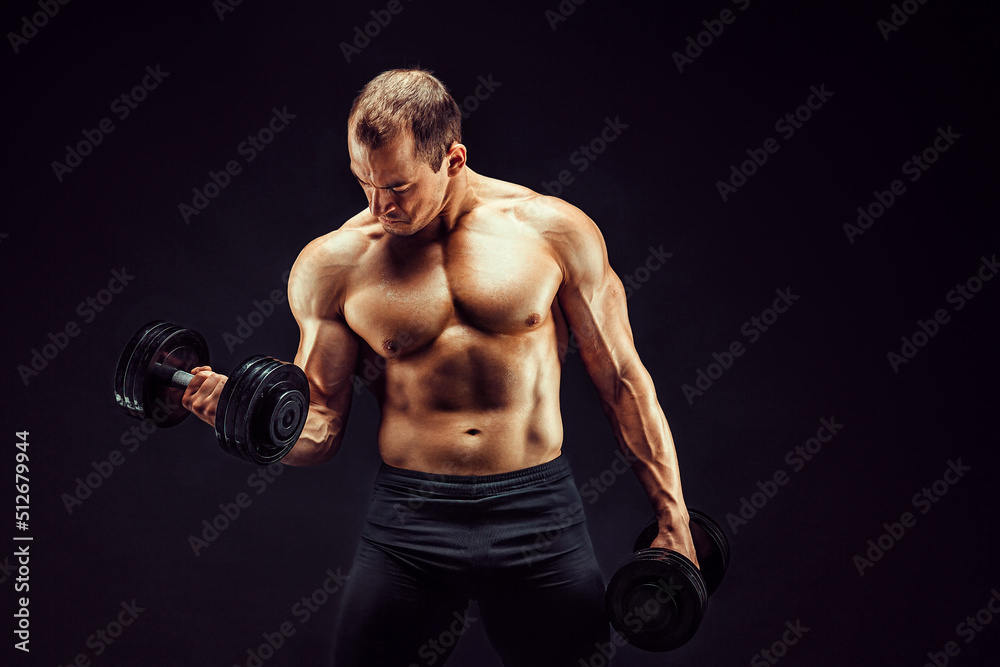 Powerful man doing the exercises with dumbbells. Photo of young man with good physique isolated on black background. 