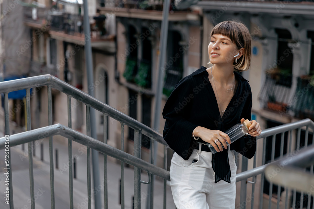 Outdoor portrait of stylish european girl with short stylish hair wearing casual clothes looking aside with lovely smile. Pretty woman walking on street with happy emotions