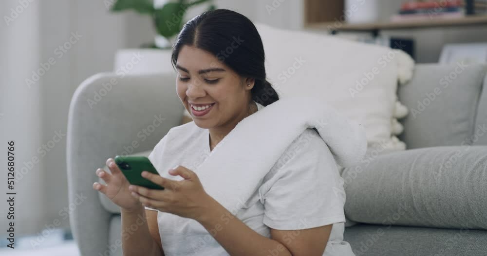 Plus size woman texting on her phone after a home workout in the living room. Smiling young chubby woman using technology to browse the internet and social media. Tracking fitness on a weight loss app Plus size woman texting on her phone after a home workout in the living room. Smiling young chubby woman using technology to browse the internet and social media. Tracking fitness on a weight loss app