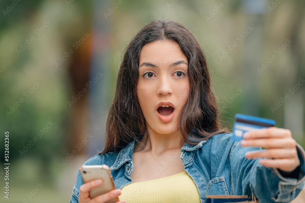 girl with cell phone and credit card with a surprised or astonished expression girl with cell phone and credit card with a surprised or astonished expression