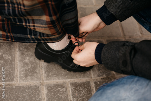 The man sat down and helps to tie the woman s shoelaces. Dominance of women  assistance to a person with limited mobility and a disabled person. The concept of care and love. High quality photo