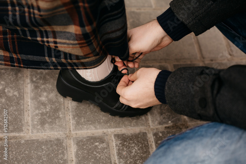 Canvas Print The man sat down and helps to tie the woman's shoelaces