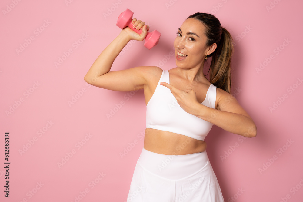fitness woman working out with dumbbell standing isolated over pink background. fitness woman working out with dumbbell standing isolated over pink background.